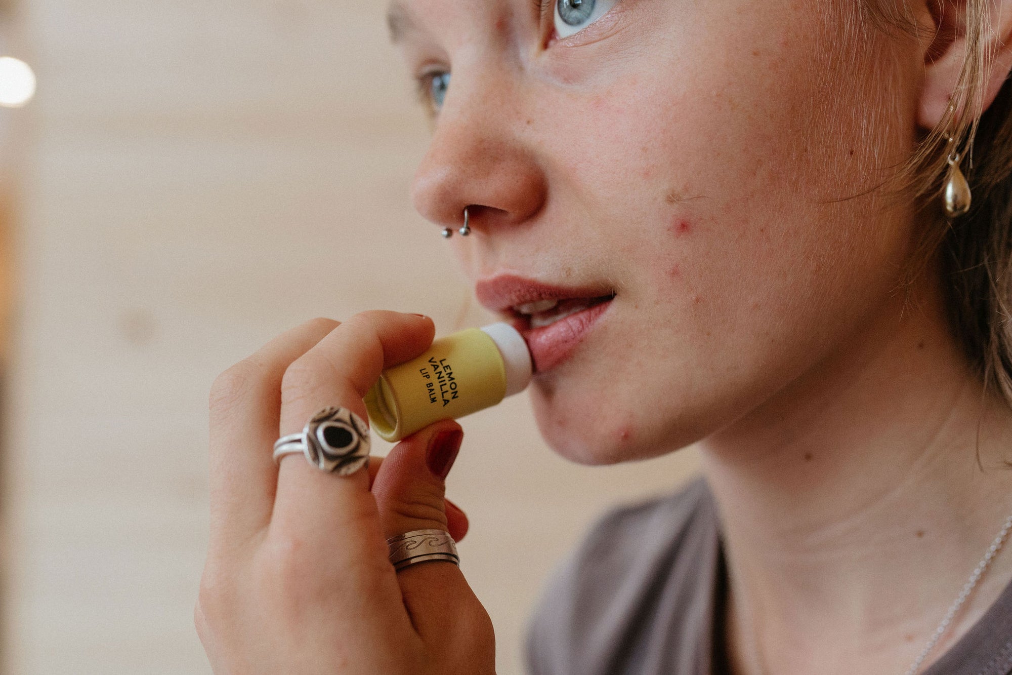 Woman with nose ring applying Organic lemon vanilla lip balm in biodegradable plastic-free tube by Good Flower Farm