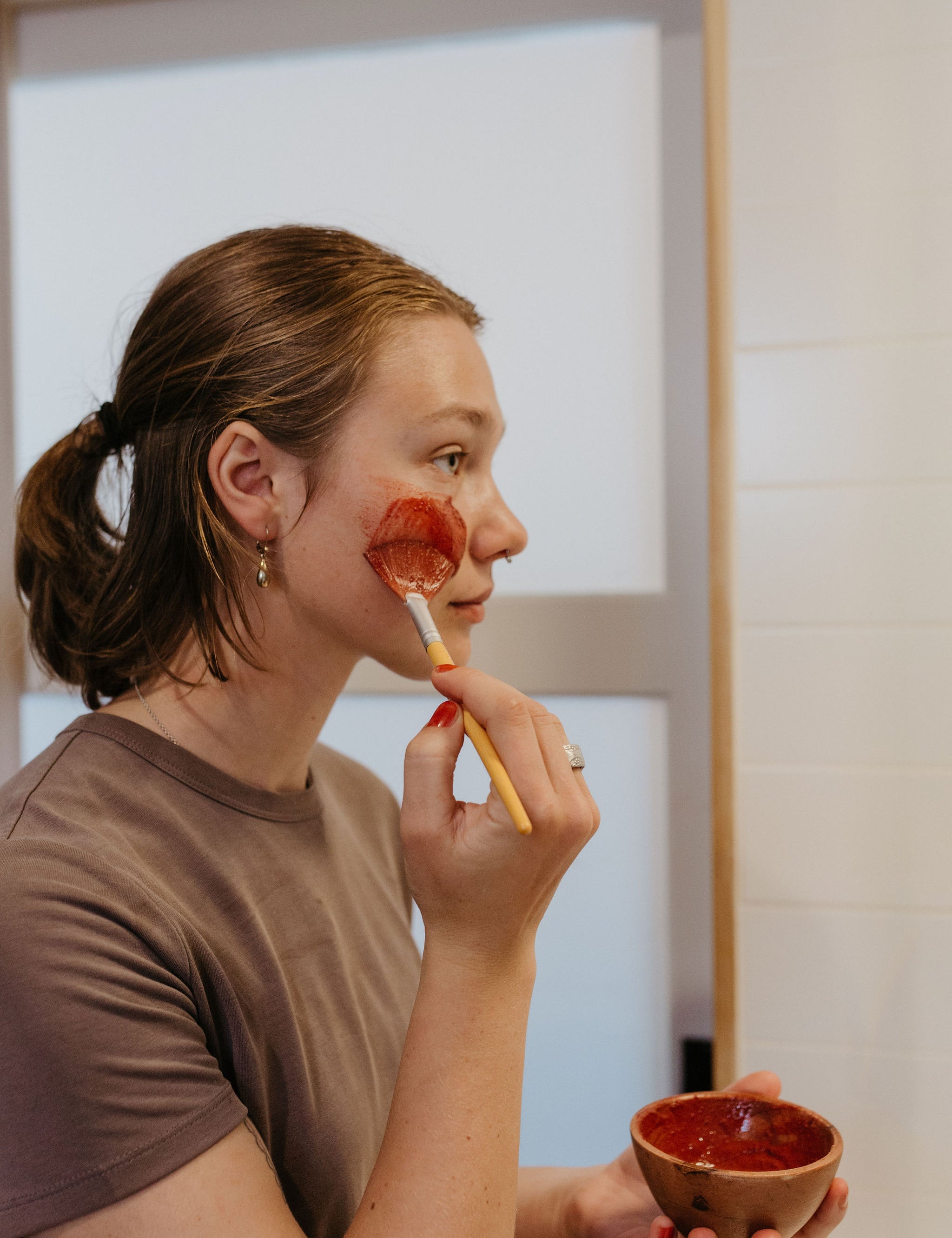 Woman applying flowers & rose clay botanical face mask by Good Flower Farm