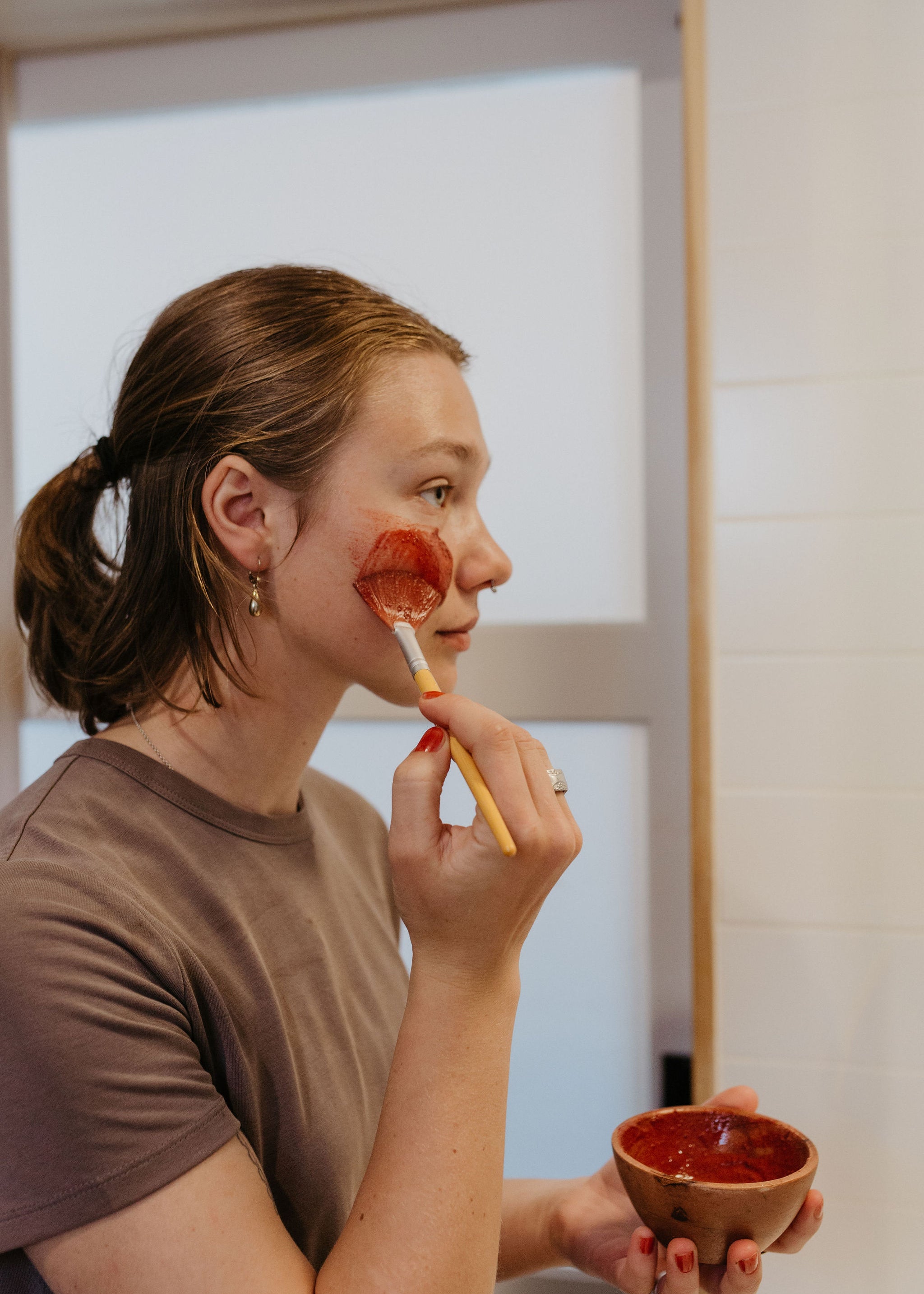 Woman applying flowers & rose clay botanical face mask by Good Flower Farm