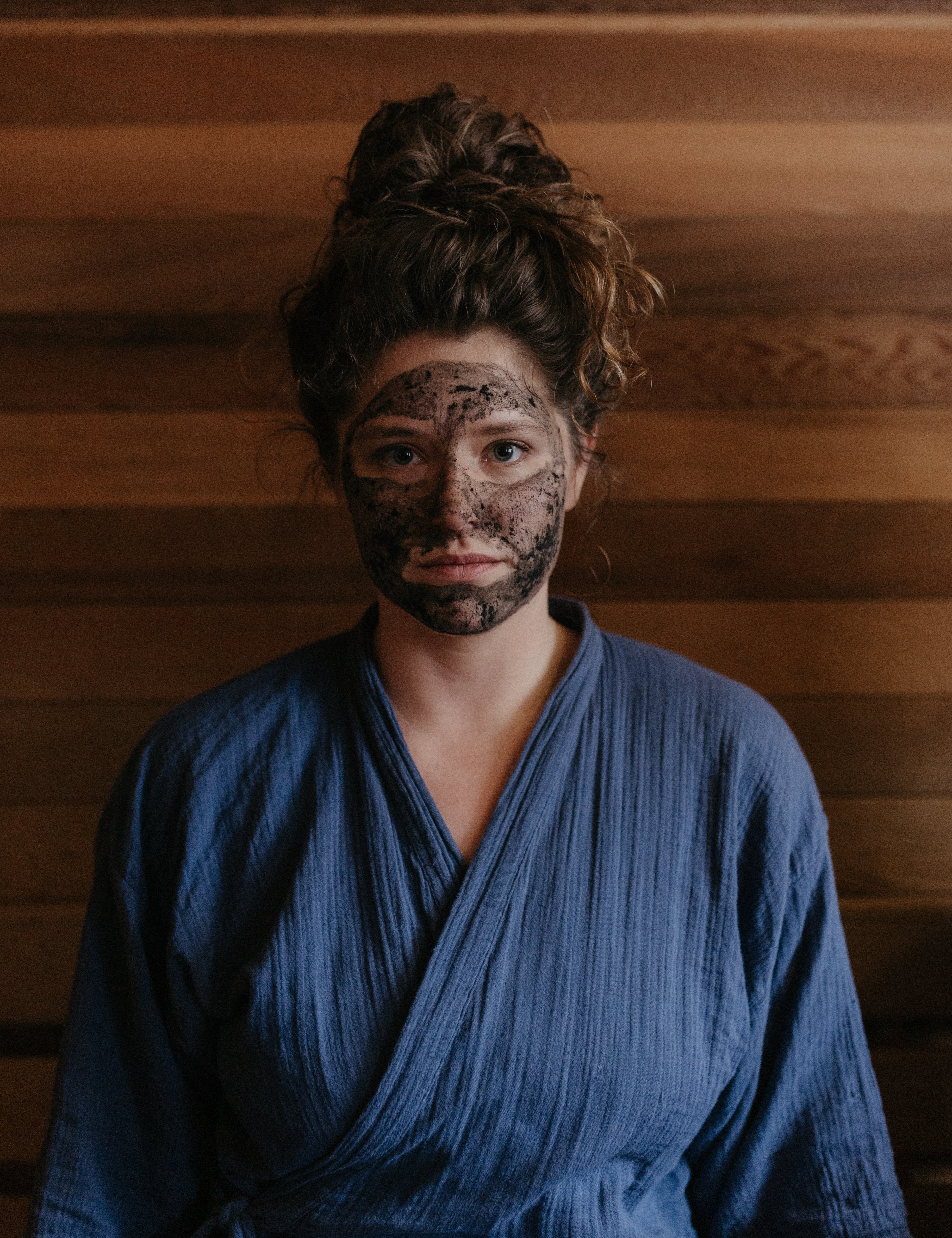 Woman in sauna in Wisconsin Wild Rice Retreat, wearing Organic activated charcoal & clay face mask by Good Flower Farm