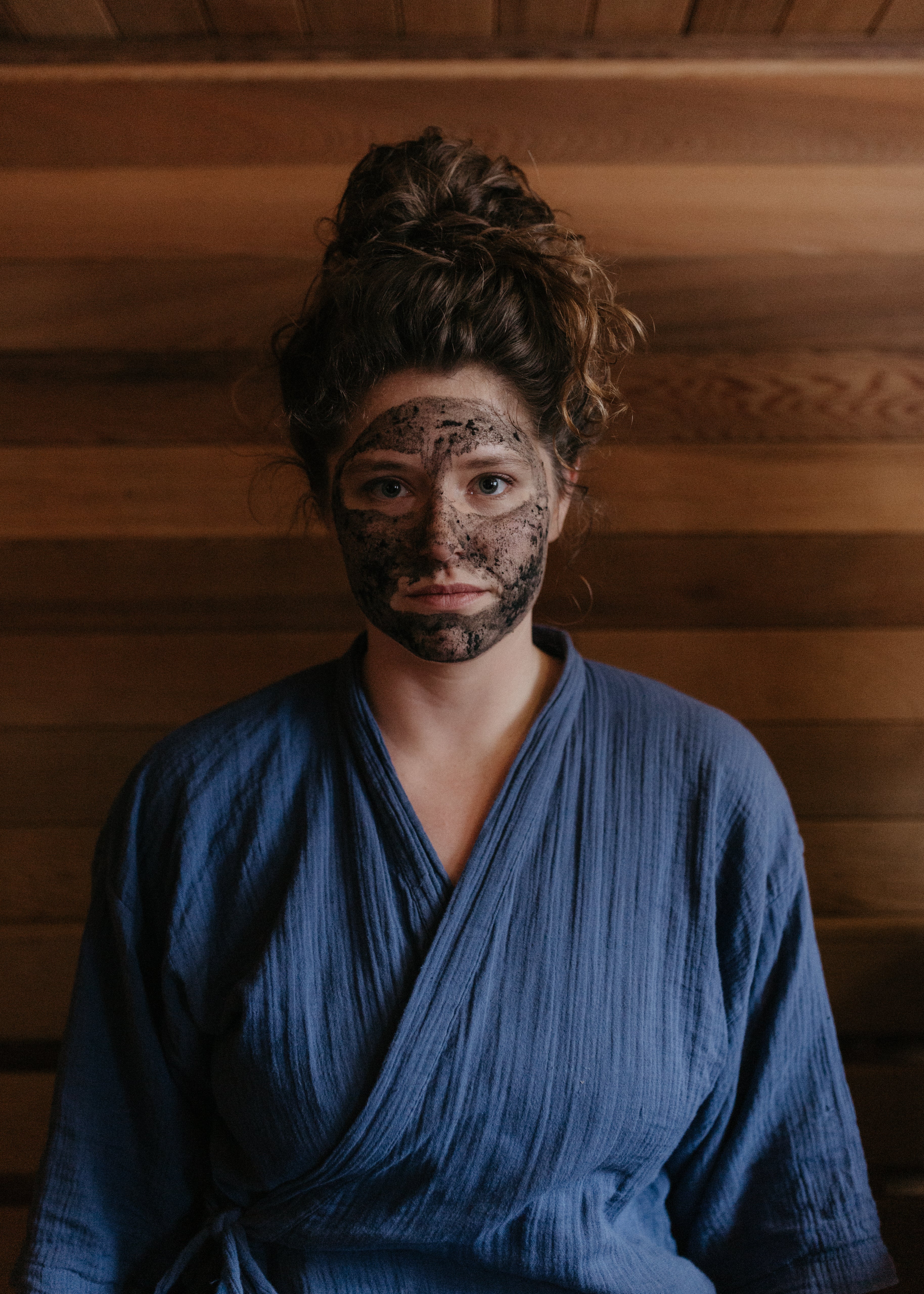 Woman in sauna in Wisconsin Wild Rice Retreat, wearing Organic activated charcoal & clay face mask by Good Flower Farm