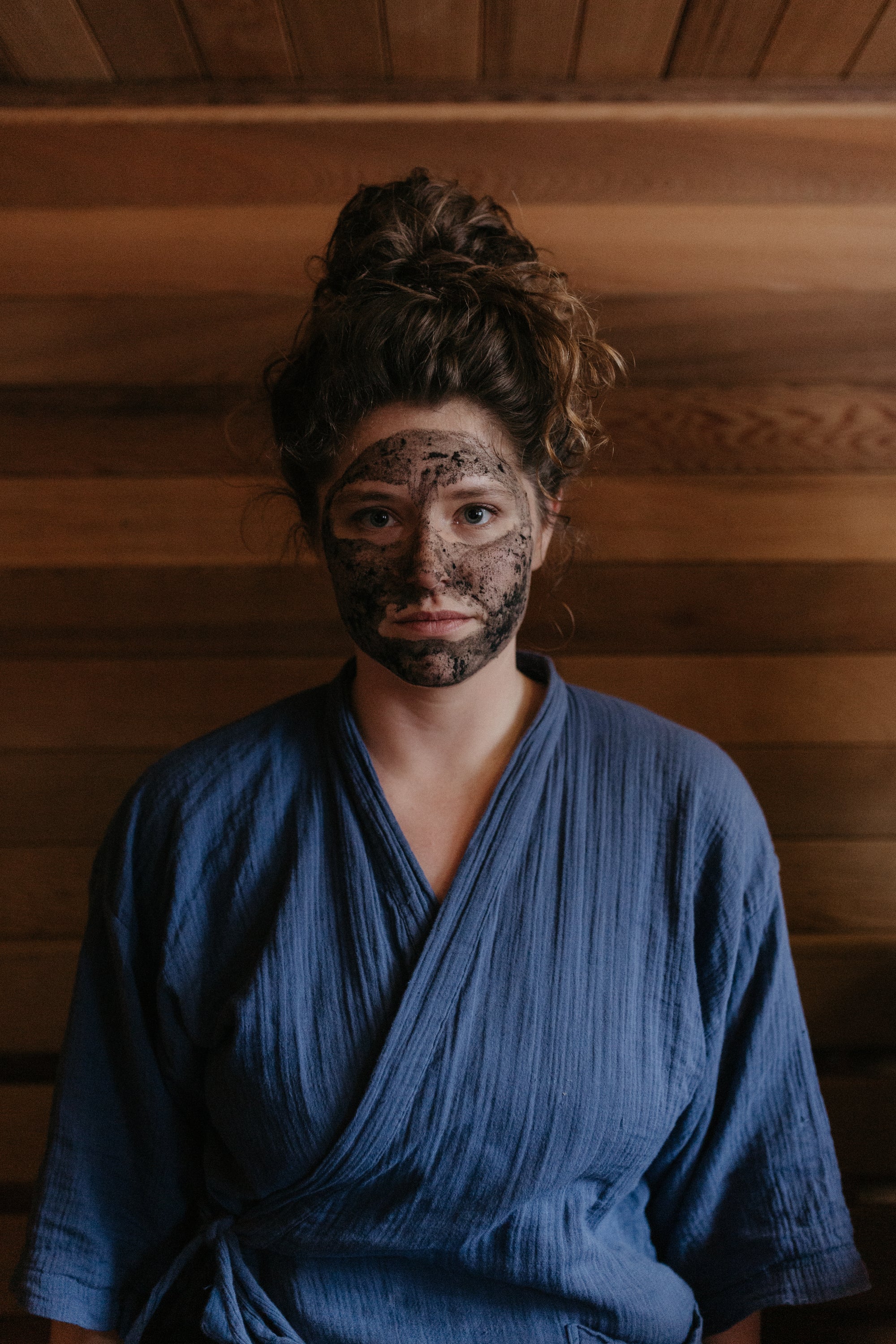 Woman in sauna in Wisconsin Wild Rice Retreat, wearing Organic activated charcoal & clay face mask by Good Flower Farm