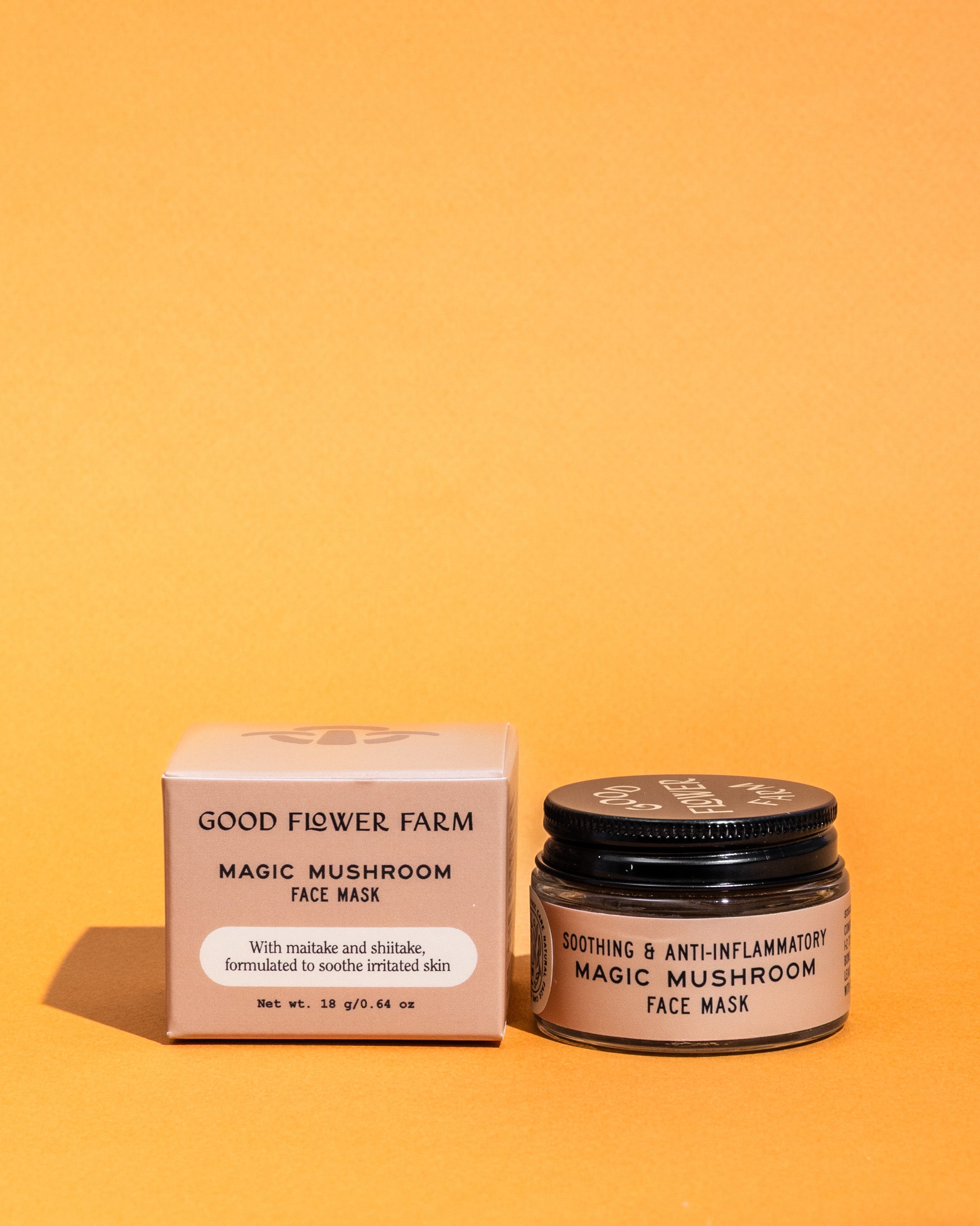 A jar of Good Flower Farm Magic Mushroom Face Mask sits by its box on an orange background. This face mask blends collagen-boosting maitake and shiitake mushrooms with rhassoul clay for soothing, anti-inflammatory care.