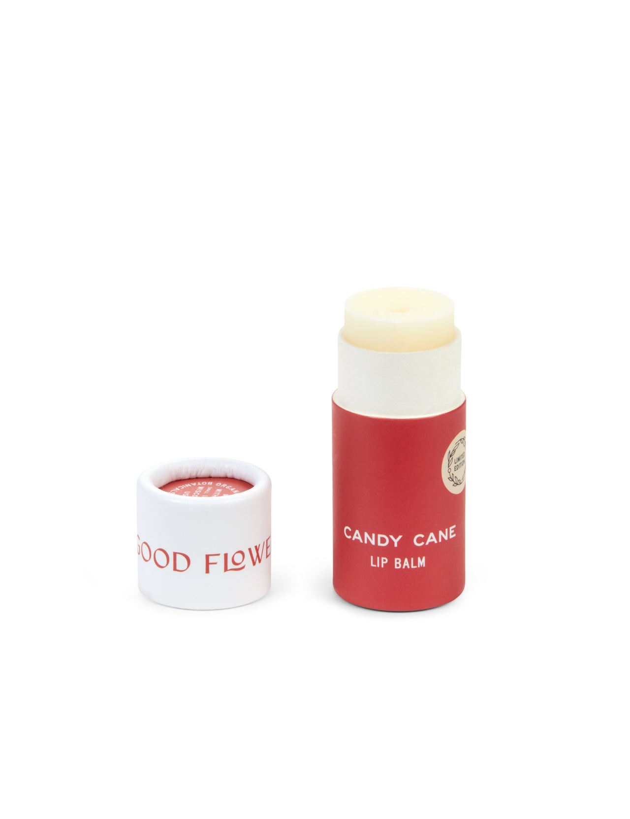 A red and white tube of SEASONAL LIMITED Candy Cane Organic Lip Balm from Good Flower Farm stands upright beside its upside-down lid, displaying the brand name. Both are set against a white background.