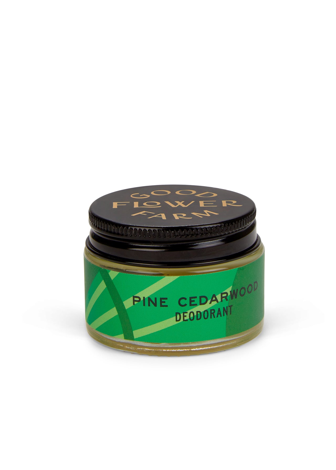 A small jar of Good Flower Farm Pine Cedarwood Deodorant with a bamboo applicator, featuring a green geometric label and black lid. This aluminum-free formula is gentle on sensitive skin. Brand name appears in gold.
