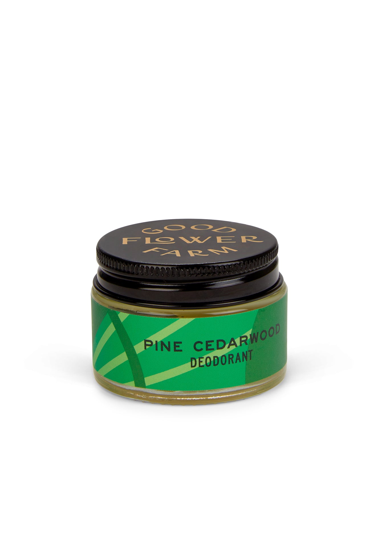 A small jar of Good Flower Farm Pine Cedarwood Deodorant with a bamboo applicator, featuring a green geometric label and black lid. This aluminum-free formula is gentle on sensitive skin. Brand name appears in gold.