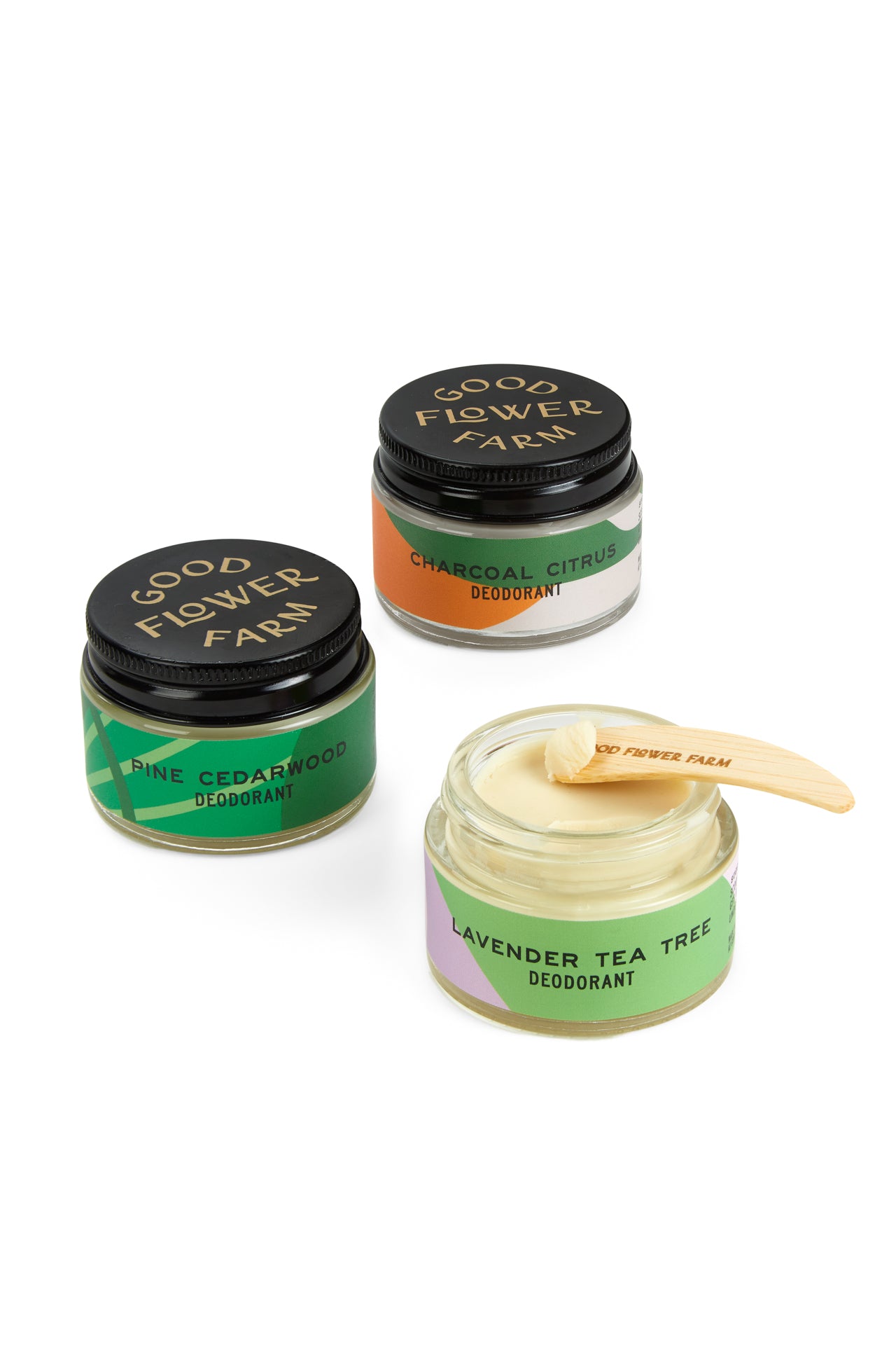 Three jars of Good Flower Farm Pine Cedarwood Deodorant, including one open with a bamboo applicator—aluminum free and gentle for sensitive skin—are displayed against a white background.