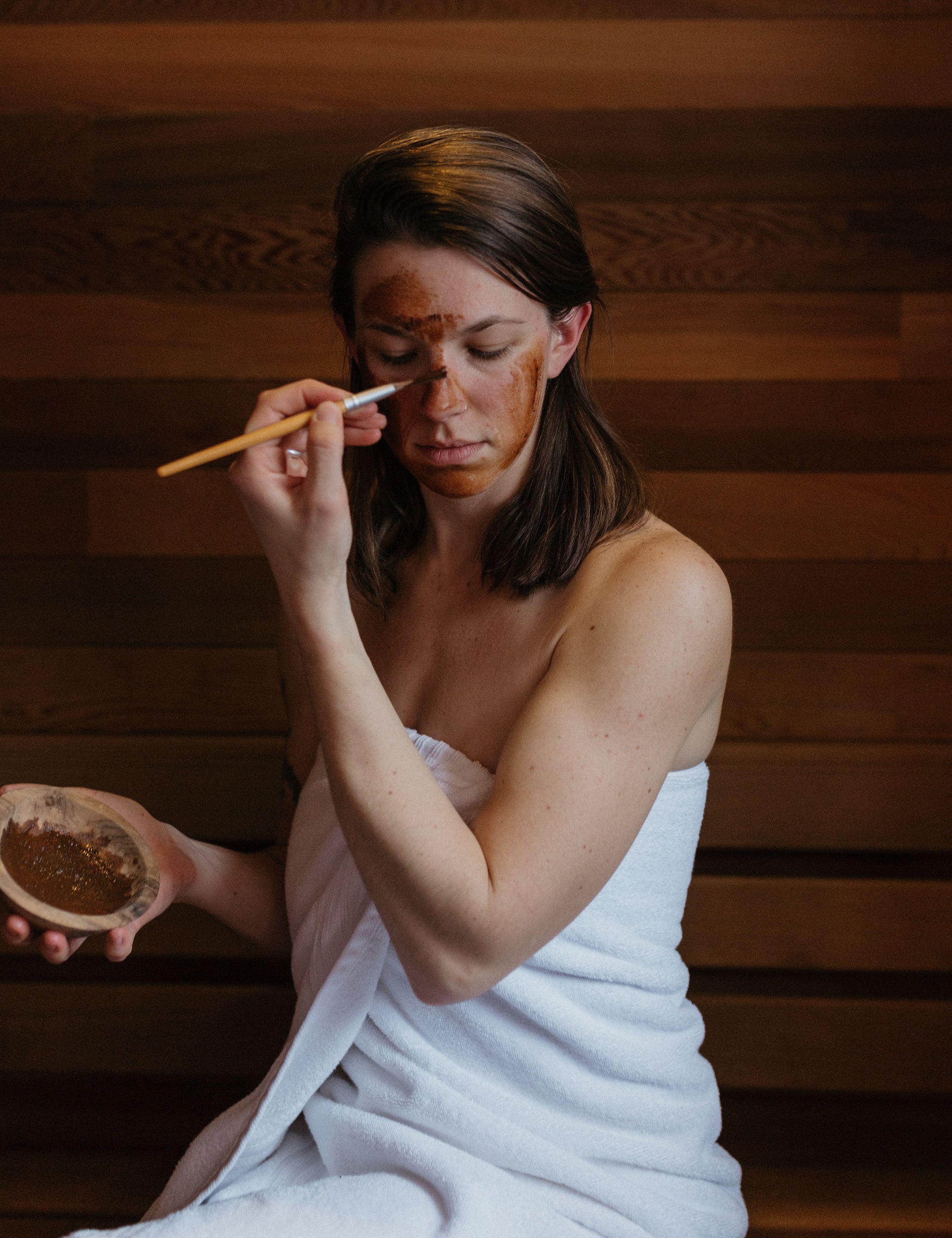 Woman applying face mask in sauna: Magic Mushroom organic botanical clay face mask by Good Flower Farm