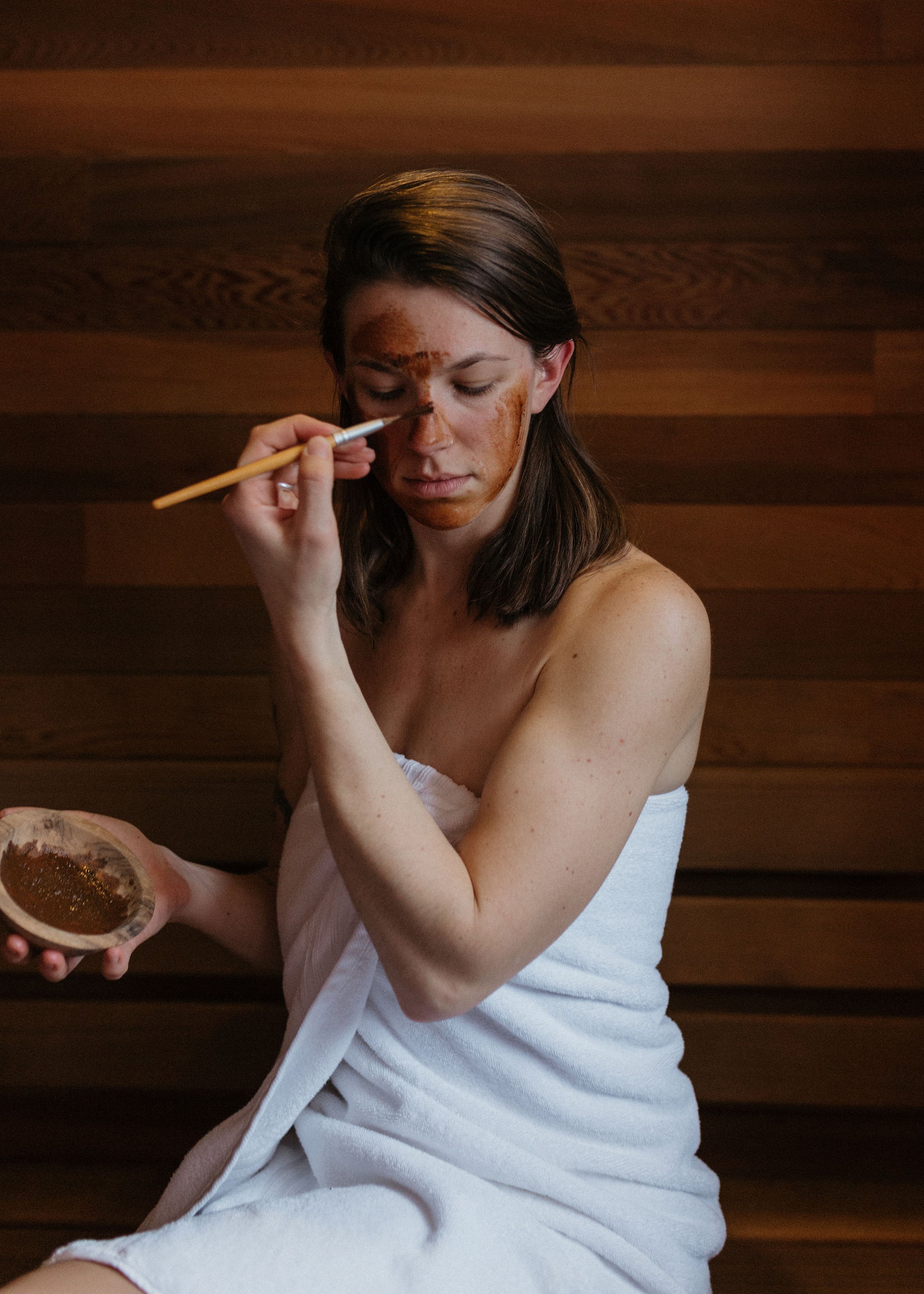 Woman applying face mask in sauna: Magic Mushroom organic botanical clay face mask by Good Flower Farm