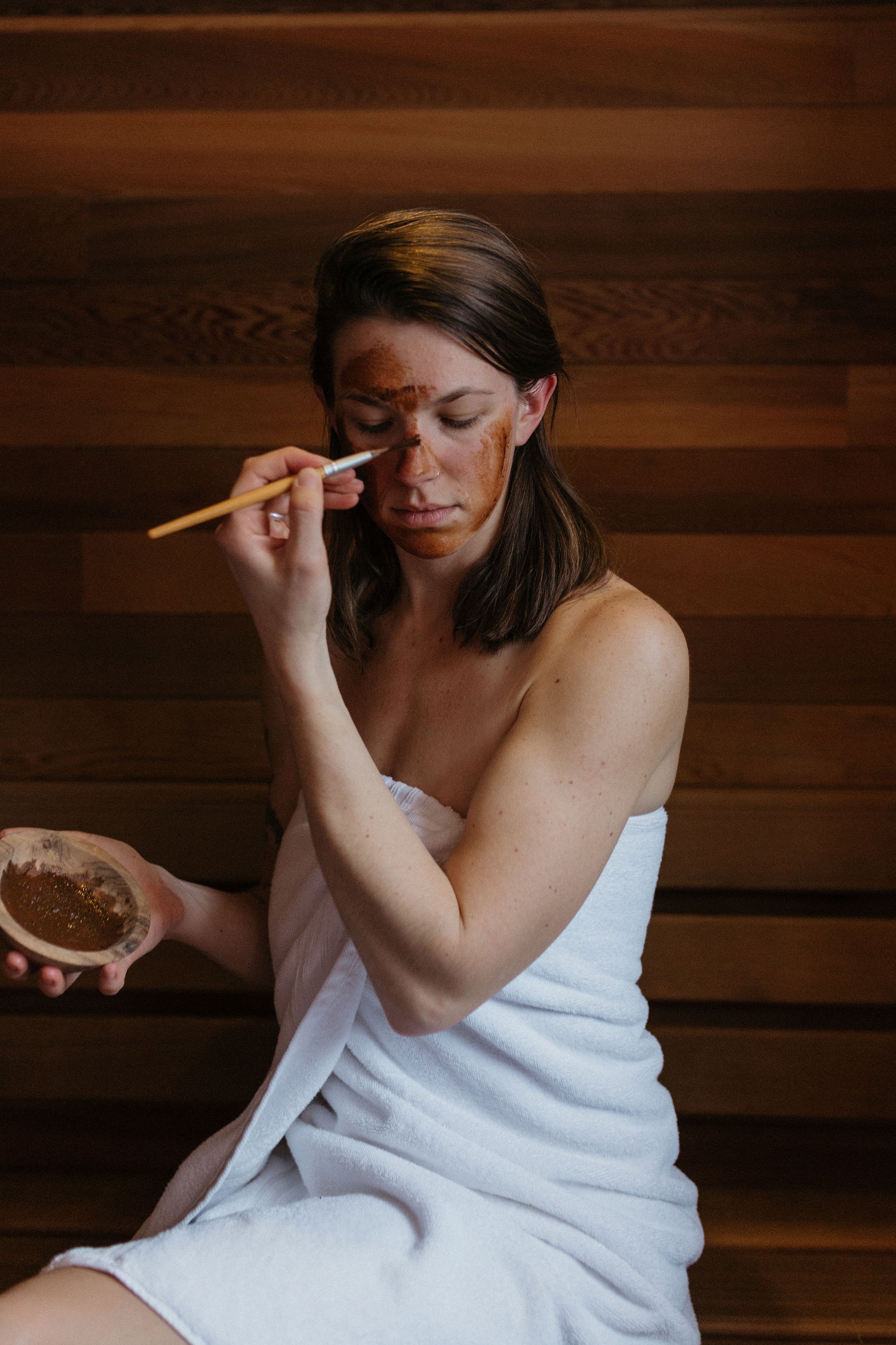 Woman applying face mask in sauna: Magic Mushroom organic botanical clay face mask by Good Flower Farm