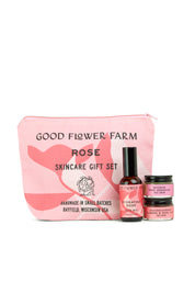 A pink Good Flower Farm Rose Skincare Gift Set cosmetic bag stands behind three floral essentials: Hydrating Rose Facial Mist, Brightening Rose Cream, and Nourishing Face Mask.