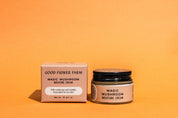 A jar and box from the good-flower-farm Dry Skin Bundle: Save 15% are displayed on an orange background. The box lists ingredients and states it’s formulated for dry skin, making it ideal for facial moisturizing.