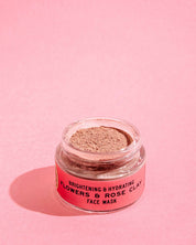 A small open jar from the good-flower-farm Dry Skin Bundle: Save 15% sits on a pink surface, the label visible and powdery product inside exposed—an ideal companion to moisture cream for dry skin and facial moisturizing.