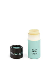 A Rainbow Organic Lip Balm from Good Flower Farm, shown in a light blue biodegradable wrapper with its black cap off and beside it on a white background; this is one of six balms in the set.