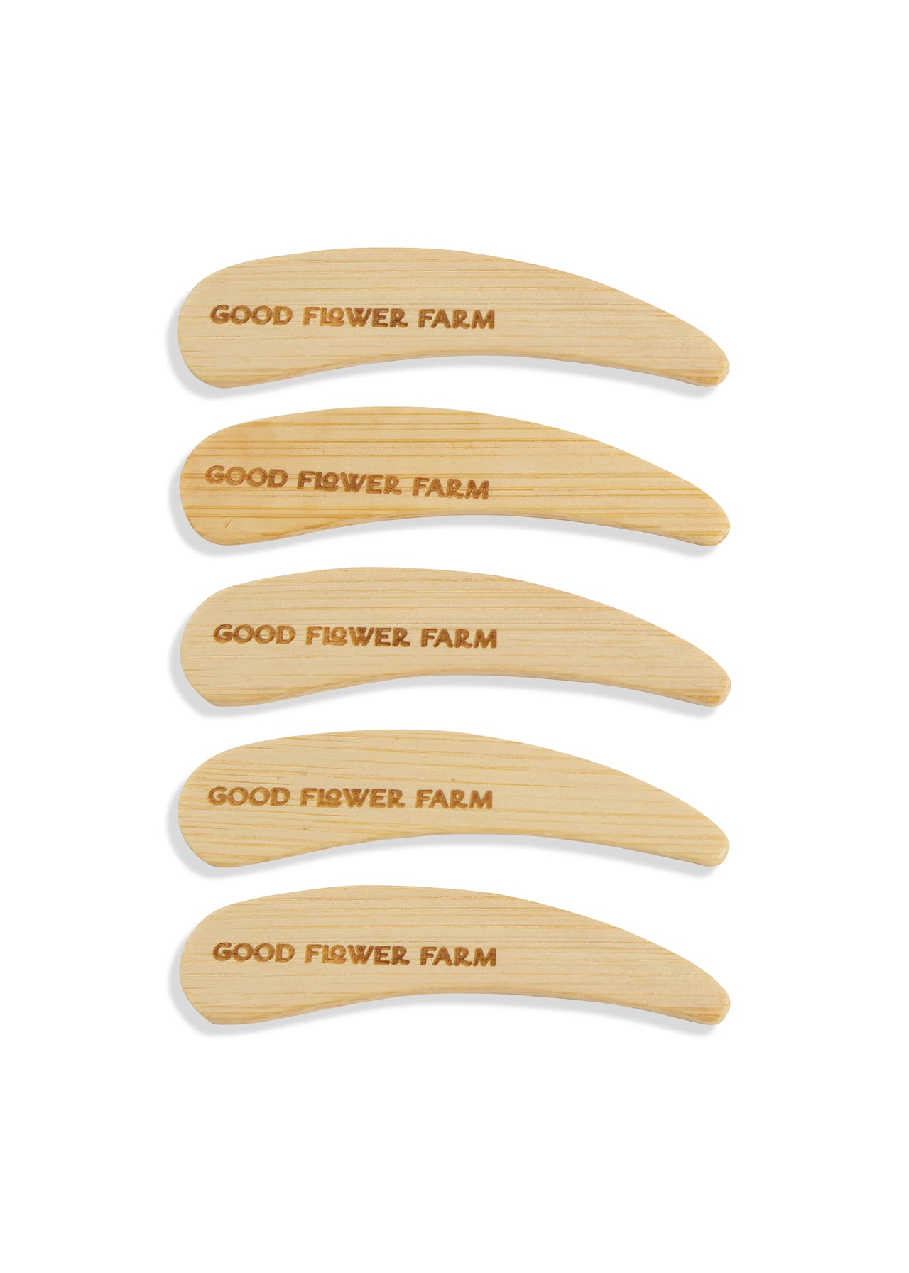 Set of 5 or 10 Good Flower Farm Reusable Bamboo Spatulas, engraved with the brand name, are neatly stacked on a white background—ideal as deodorant applicators or for other personal care uses.